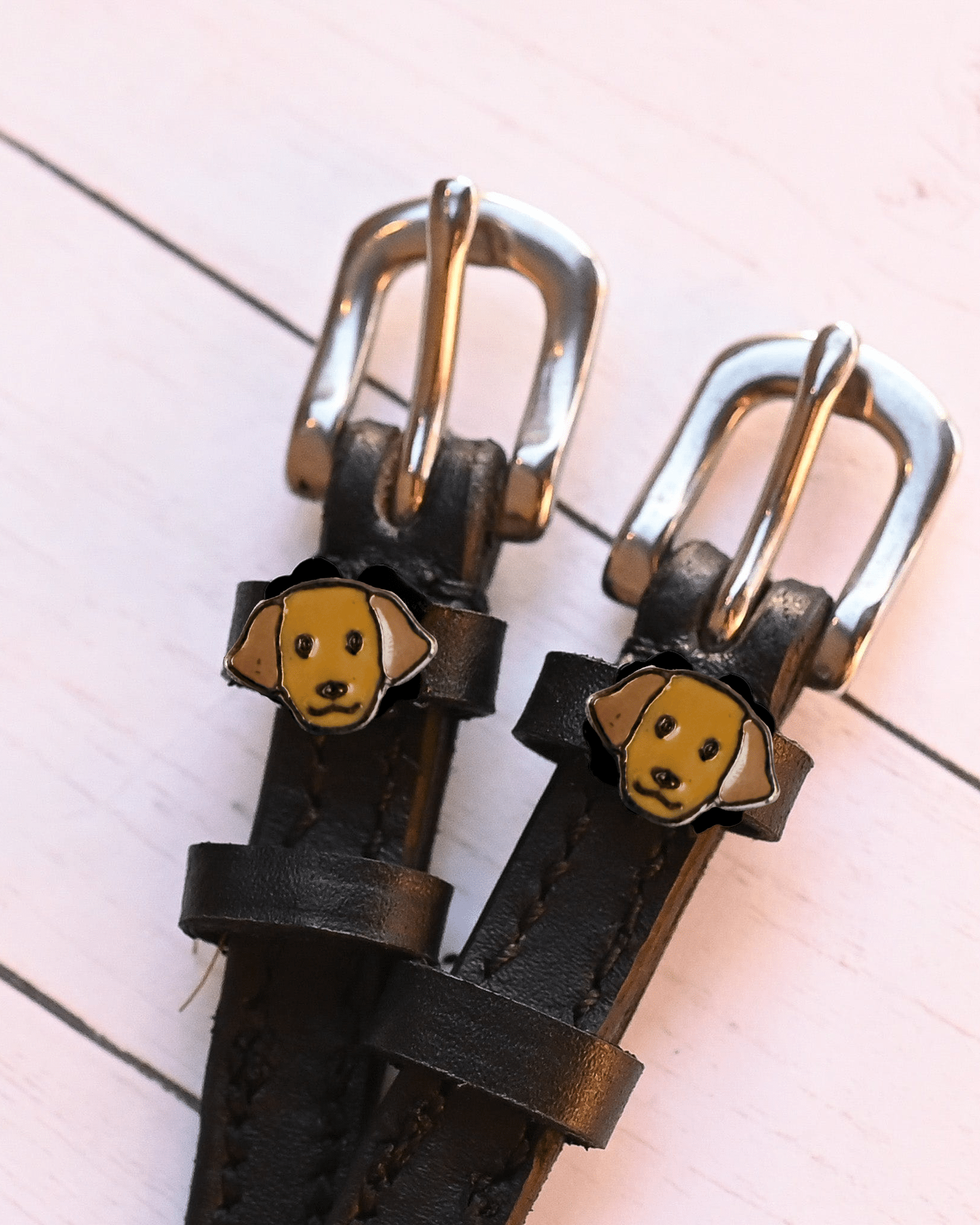 Angled close-up of golden Labrador dog charms on black leather ManeJane spur straps