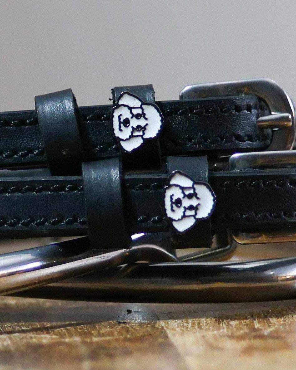 Close-up of white poodle face charms on black leather spur strap keepers
