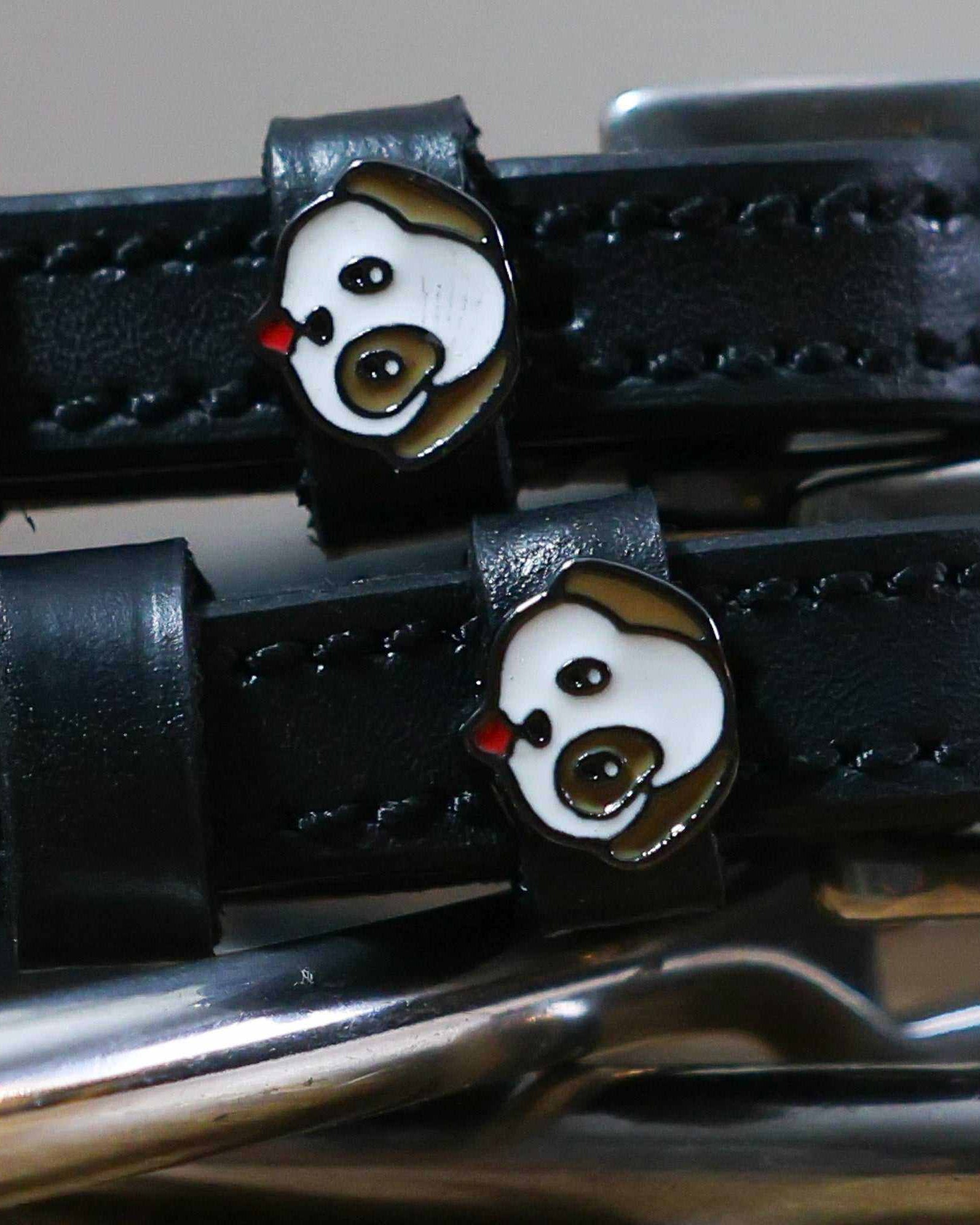 Close-up of a white-and-brown puppy face charm on a black leather spur strap