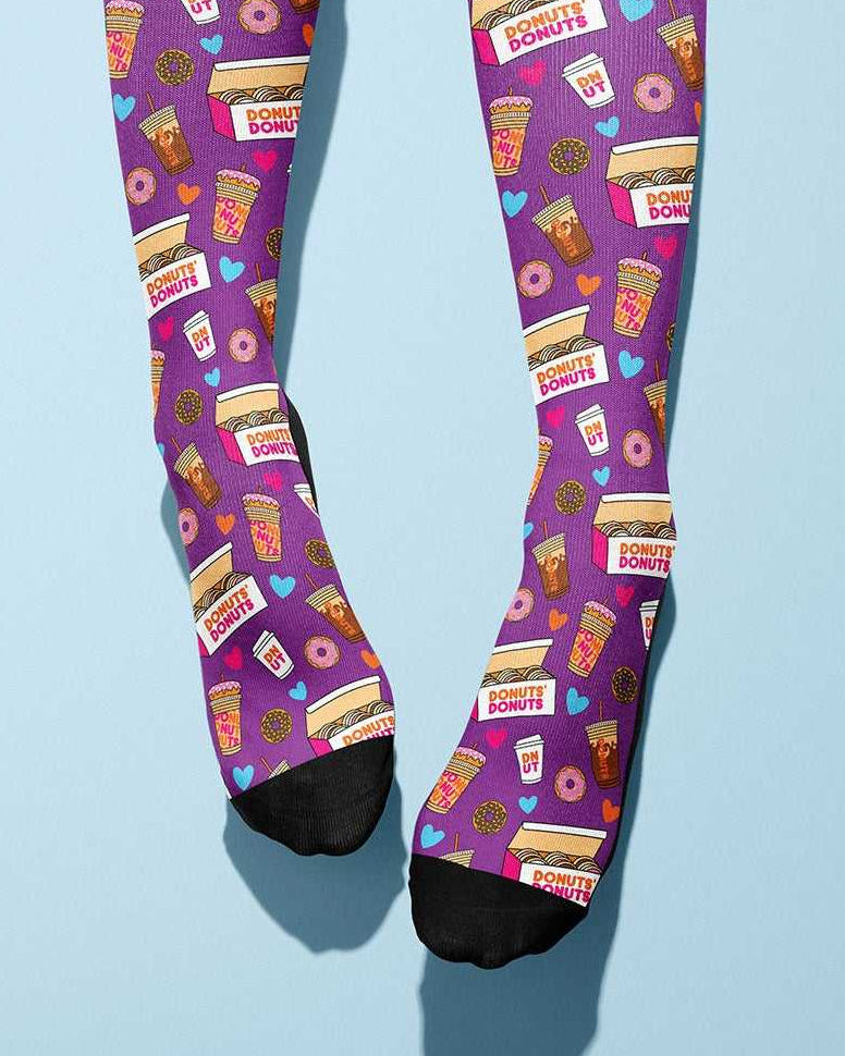 Pair of purple Donut Donutz themed socks with coffee and donut graphics on light blue background