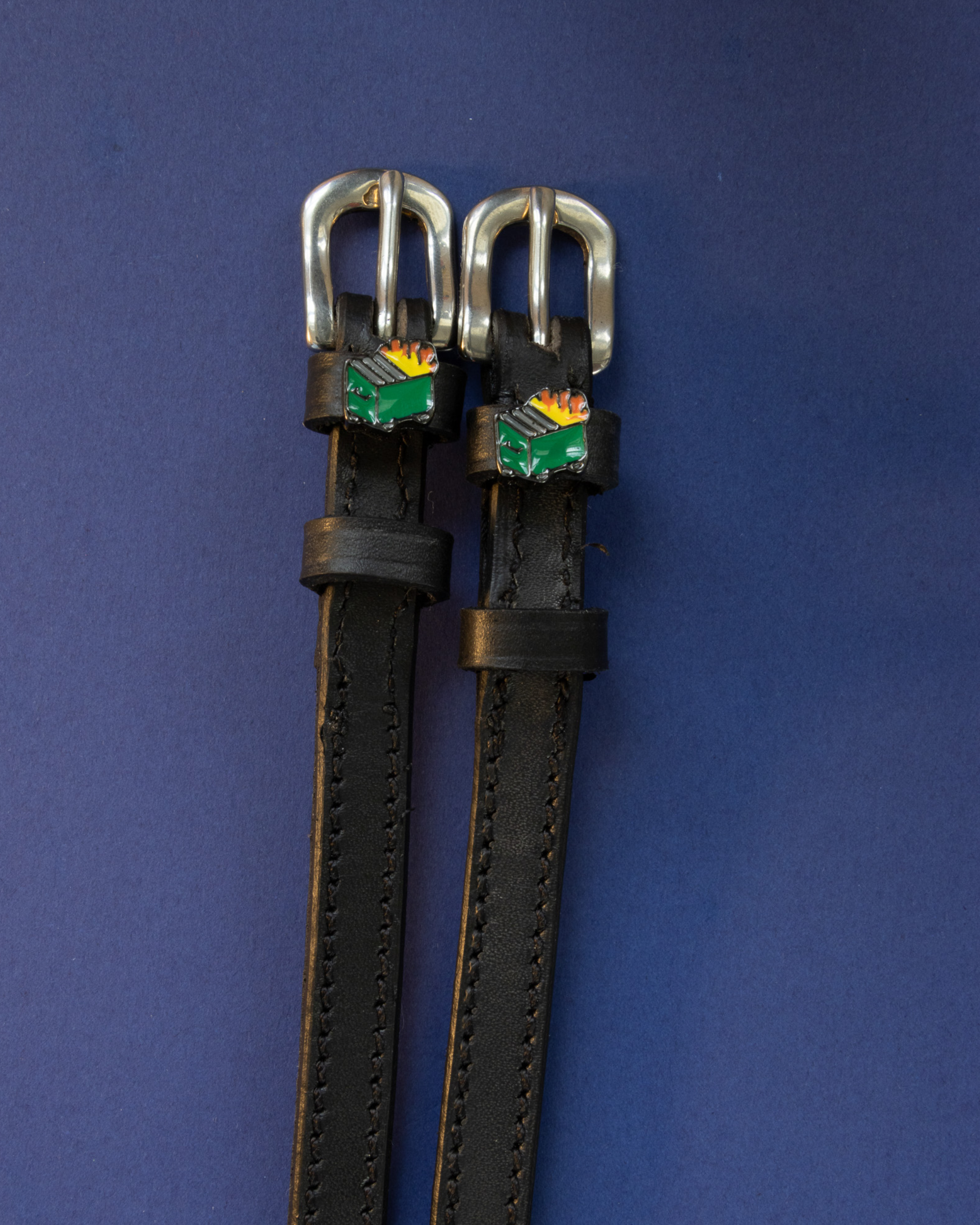 Black leather dumpster fire spur straps with silver buckles on navy blue
