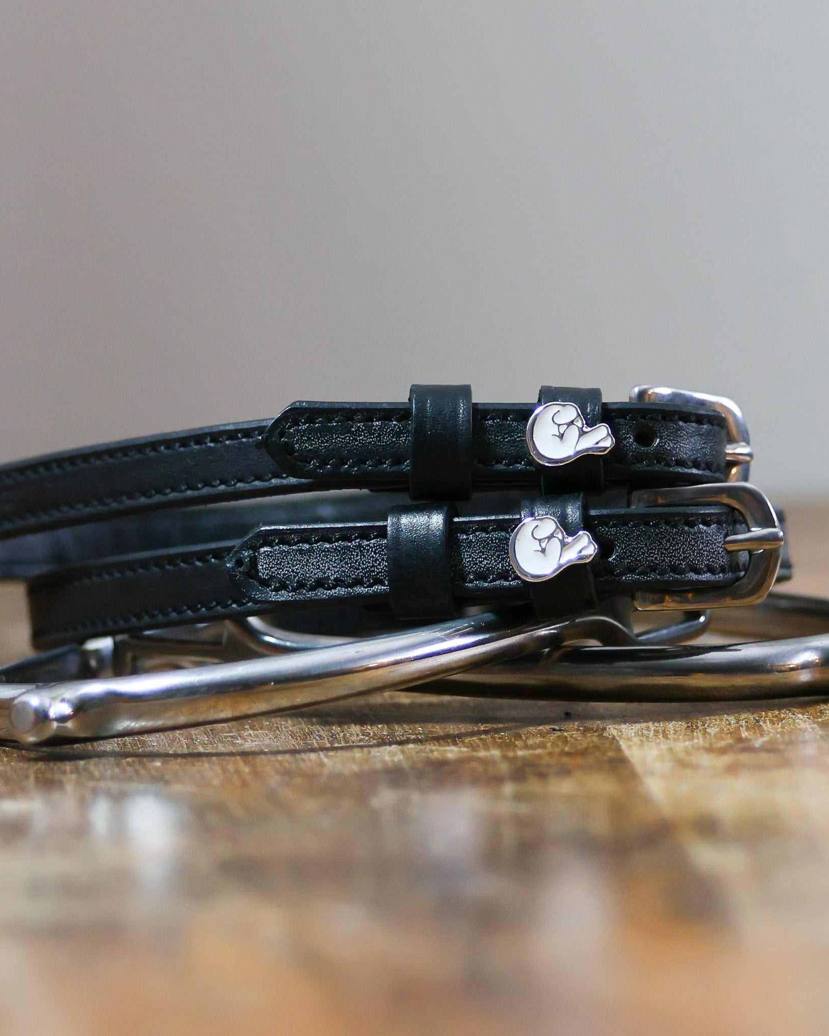 Coiled black leather spur straps and a silver spur on wood with crossed-fingers charms