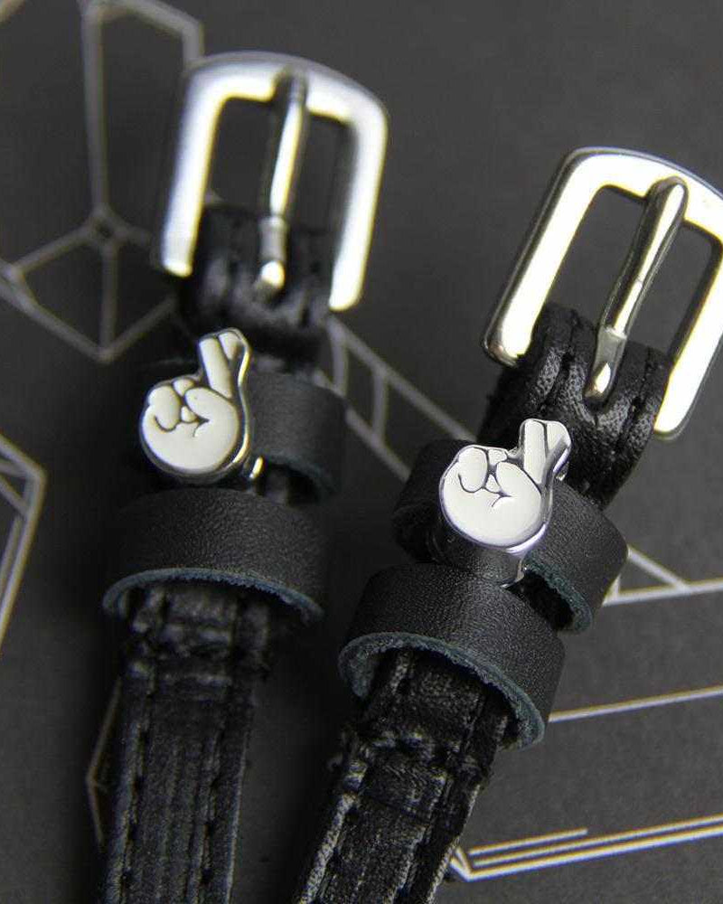 Close-up of silver buckles and crossed-fingers charms on black leather spur straps