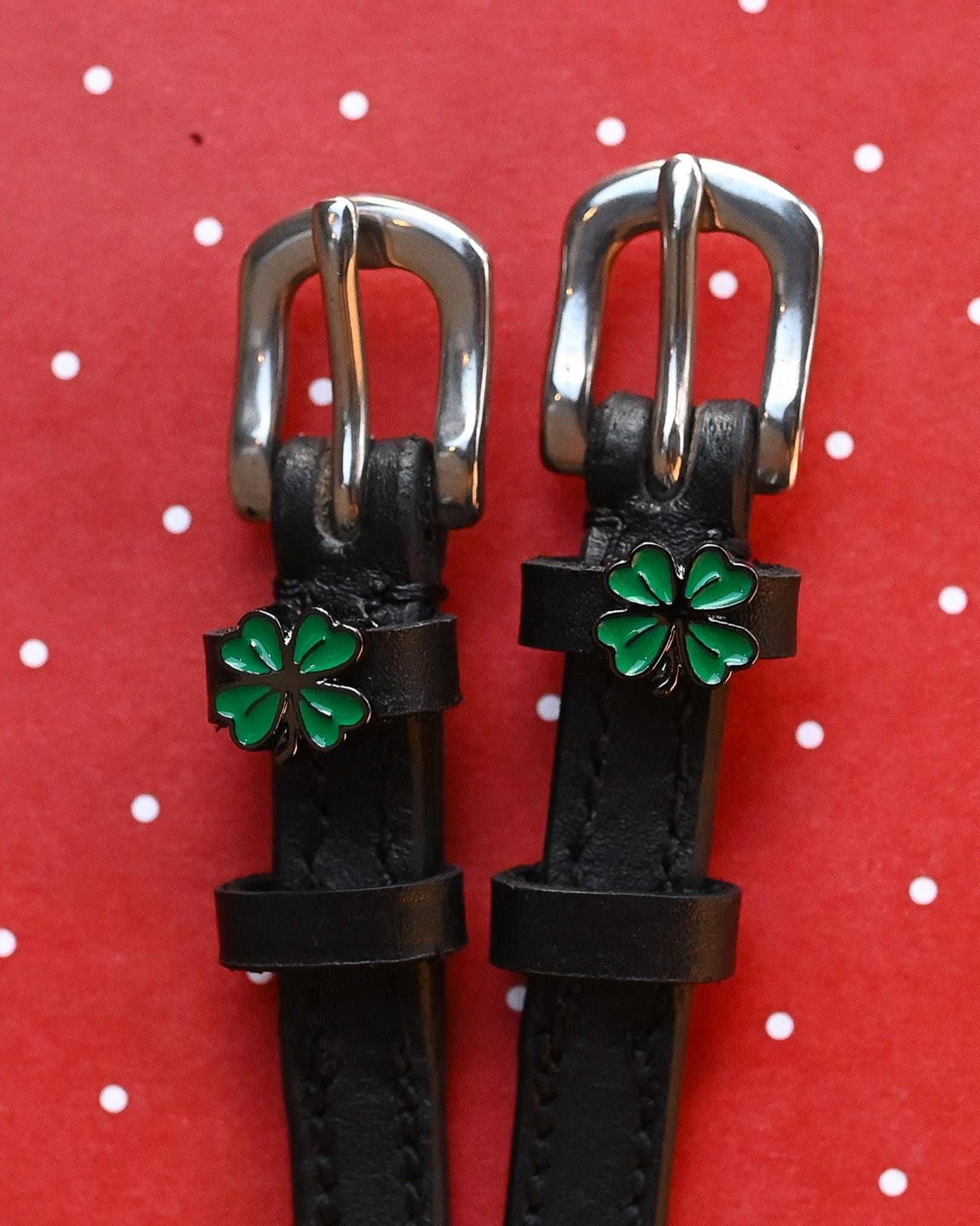 ManeJane four leaf clover spur straps with green charms on a red polka-dot background