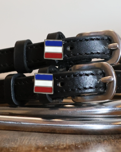Close-up of enamel French tricolor flag charms on black leather spur strap keepers