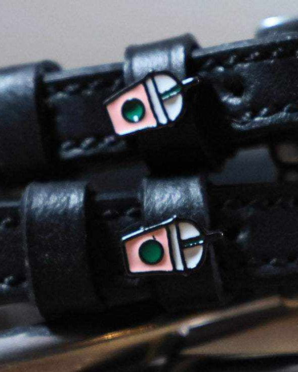 Close-up of iced coffee frappe cup charms on black leather spur strap keepers