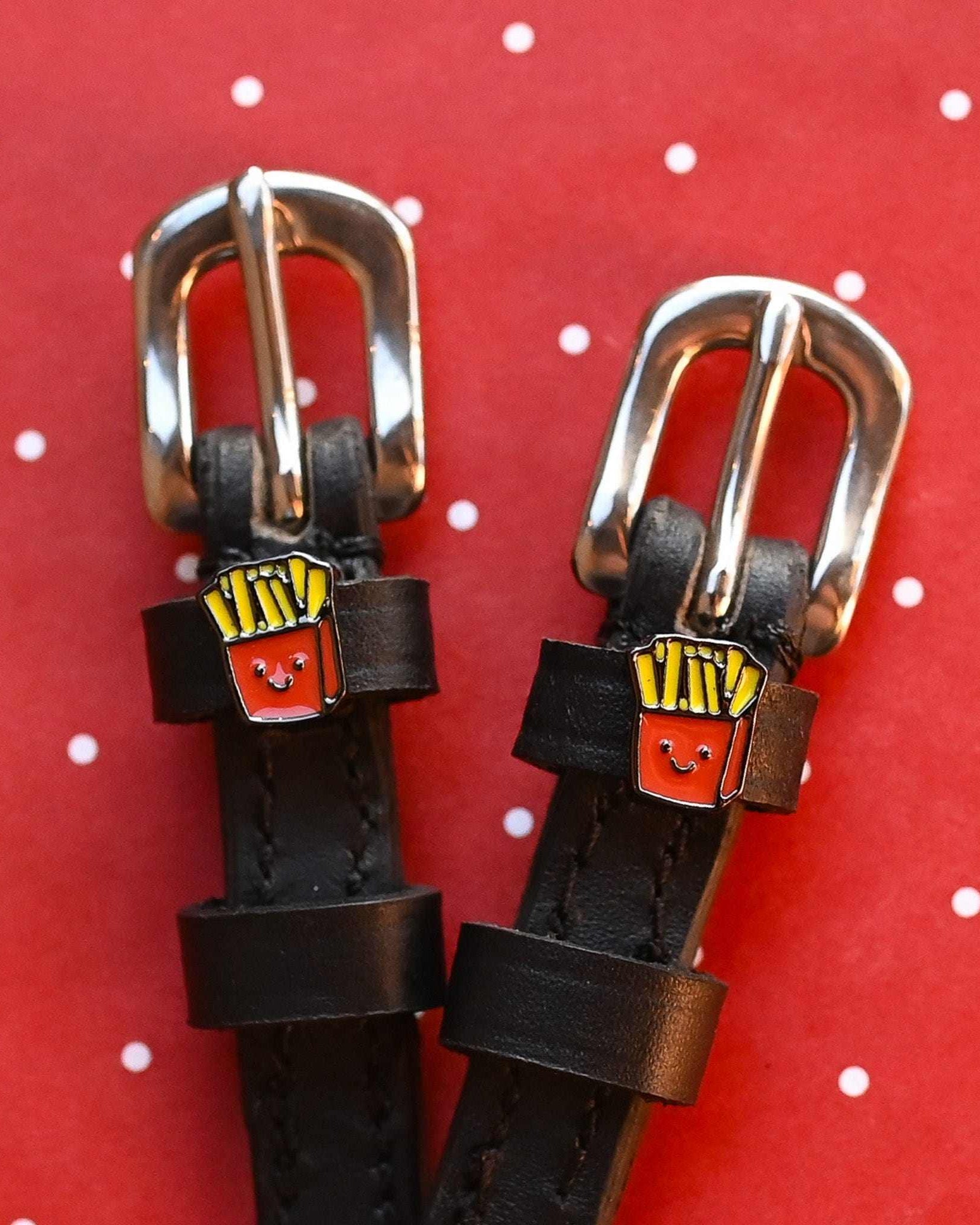French Fries spur straps with rose gold buckles and fry charms on a red polka-dot backdrop