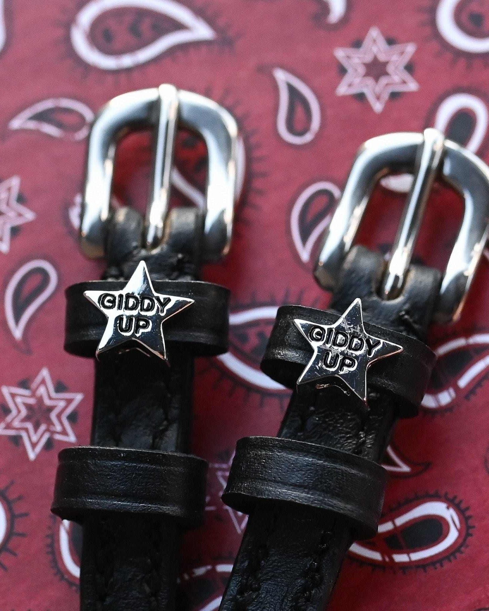 Black leather 'Giddy Up' star spur straps on a red paisley bandana background by ManeJane