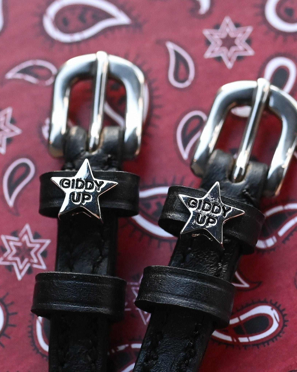 Black leather 'Giddy Up' star spur straps on a red paisley bandana background by ManeJane