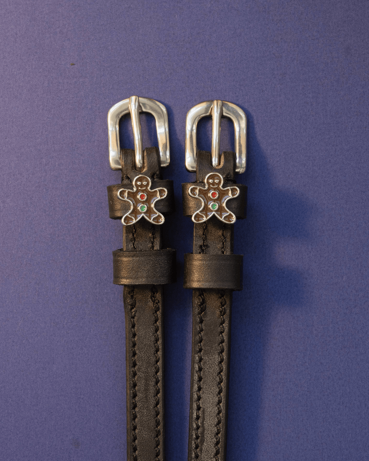 Black leather gingerbread man spur straps with silver buckles on deep purple