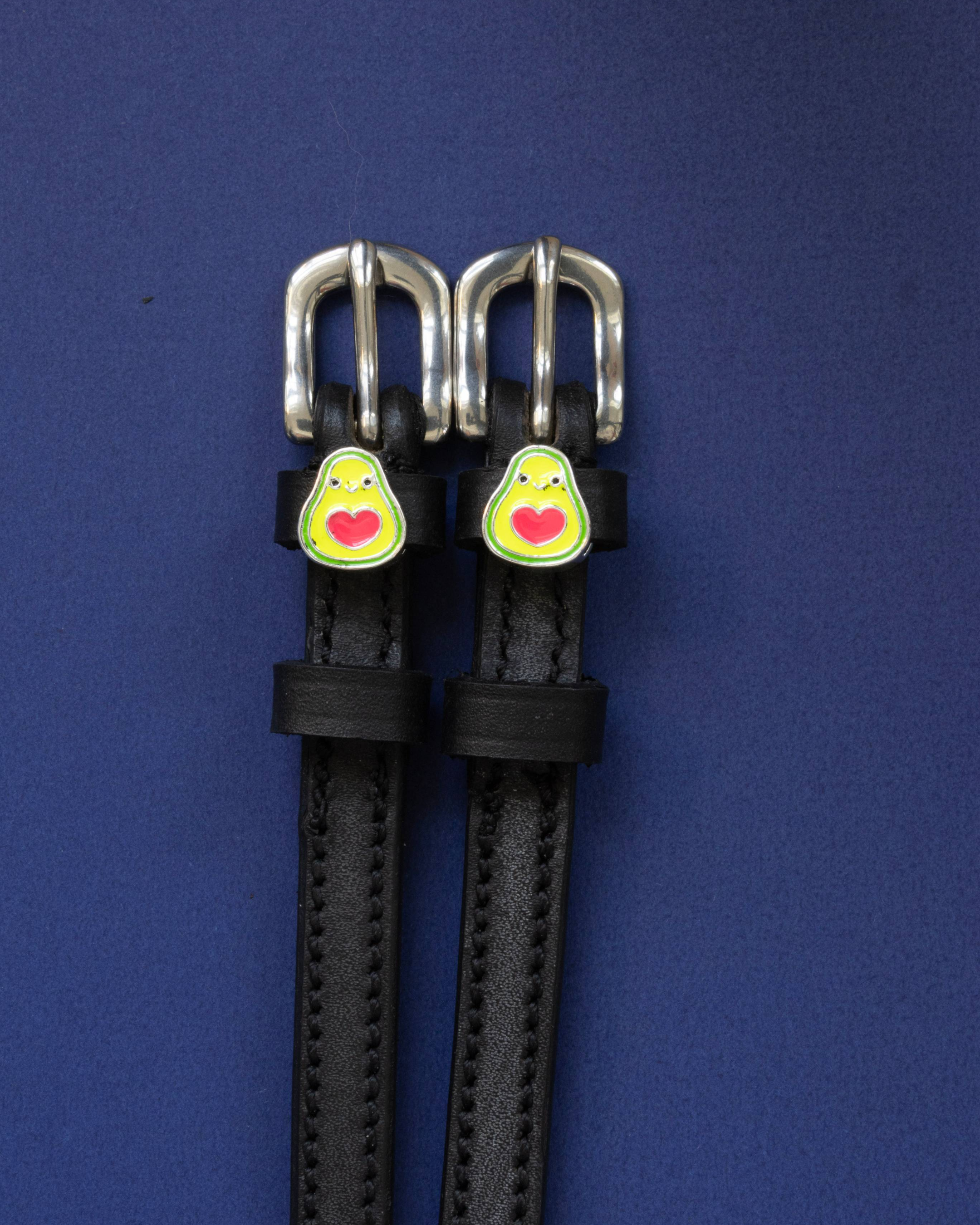 Black leather avocado spur straps with silver buckles on a navy blue background