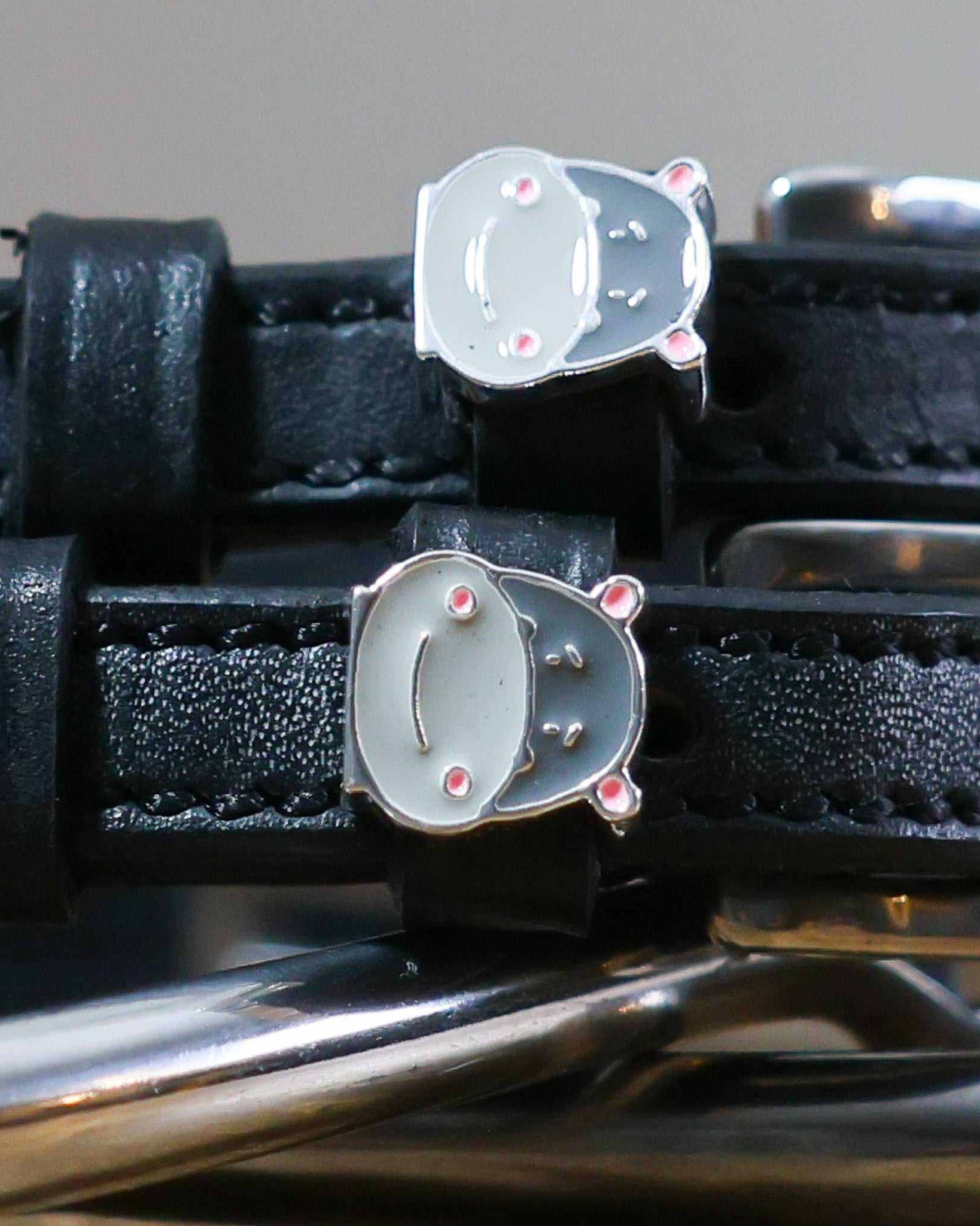 Close-up of grey hippo face charms on black leather spur straps over spur hardware