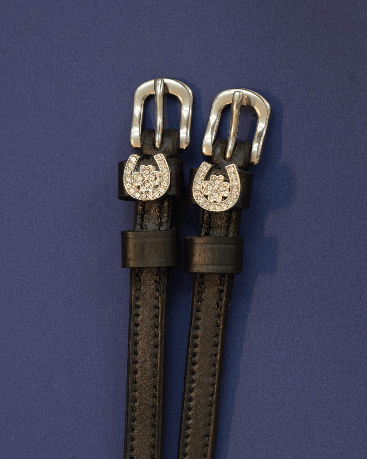 Black leather ManeJane spur straps with crystal horseshoe and clover charms on navy