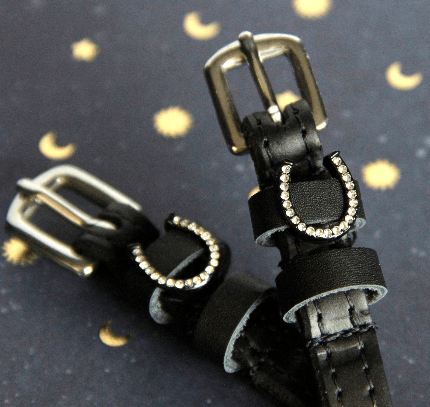 Angled close-up of crystal horseshoe spur straps on a starry moon-print backdrop