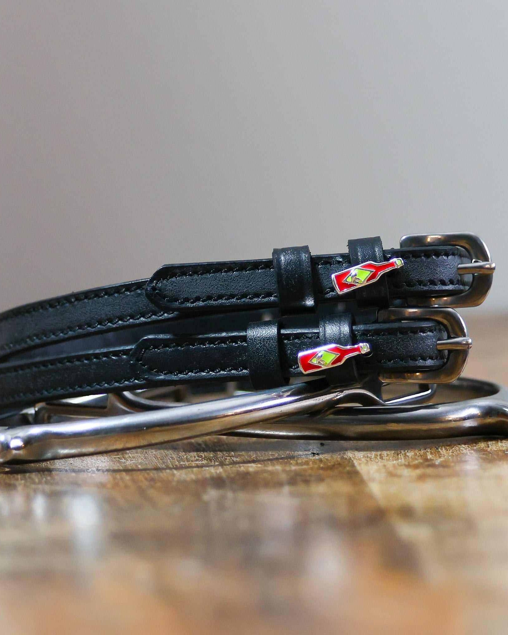 Coiled black leather spur straps and a silver spur on wood with hot sauce charms