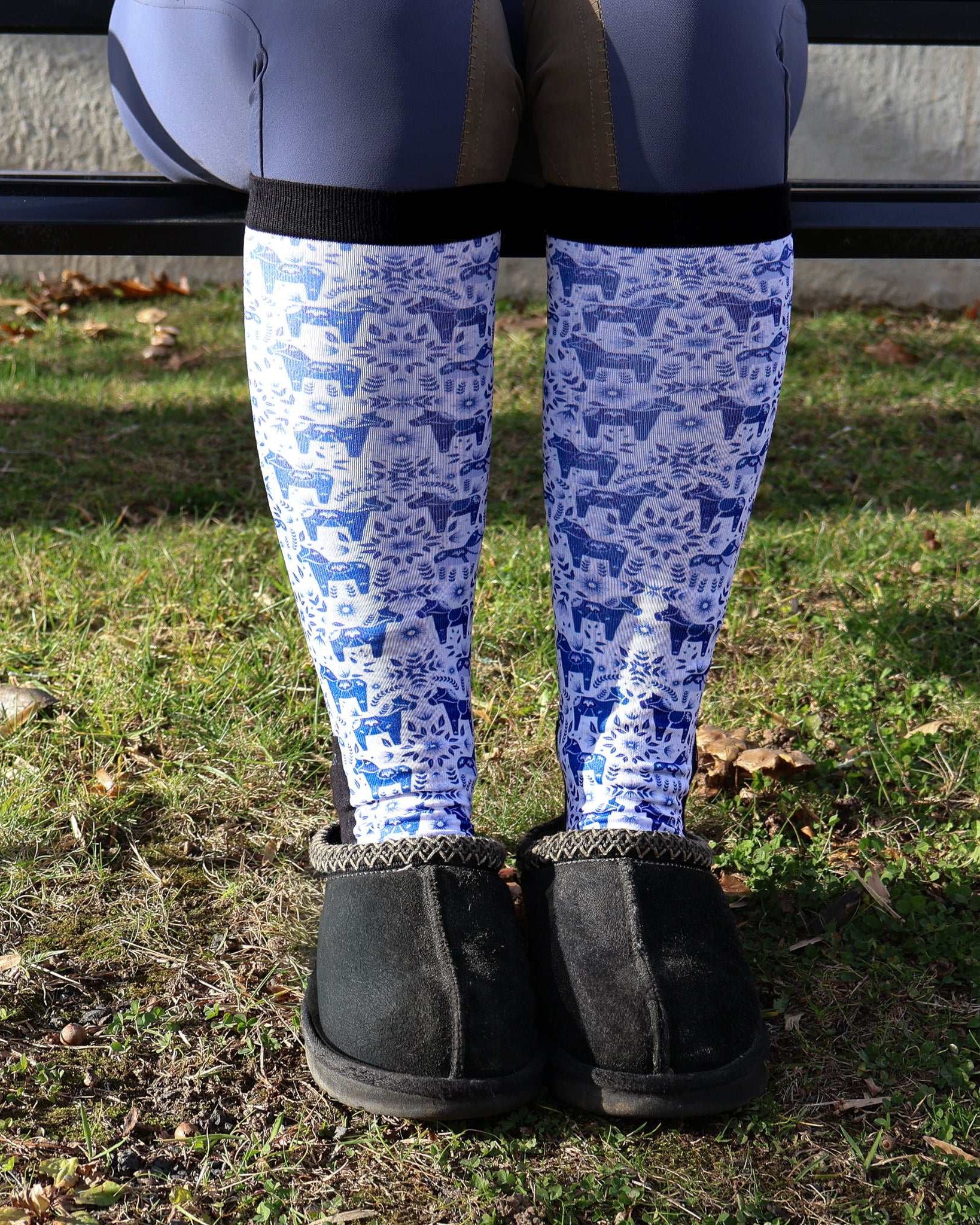 Limited Edition Pony Island Dala Horses Socks with blue folk-art pony design worn with black slippers outdoors