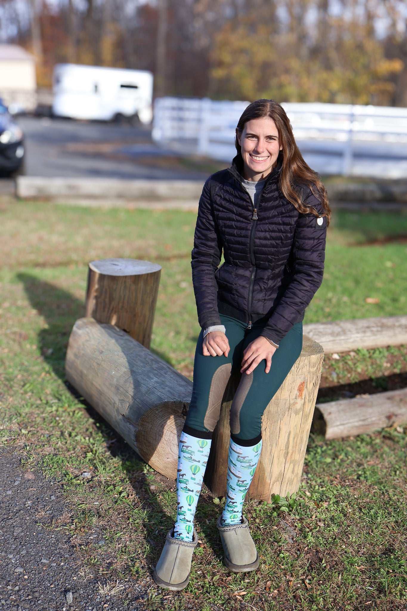 Woman sitting on log wearing Limited Edition Pony Island Pony Transport Socks with pony design in outdoor setting