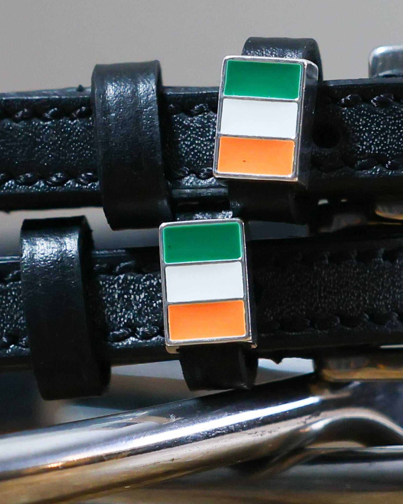 Close-up of Irish tricolor flag charms on black leather spur strap keepers
