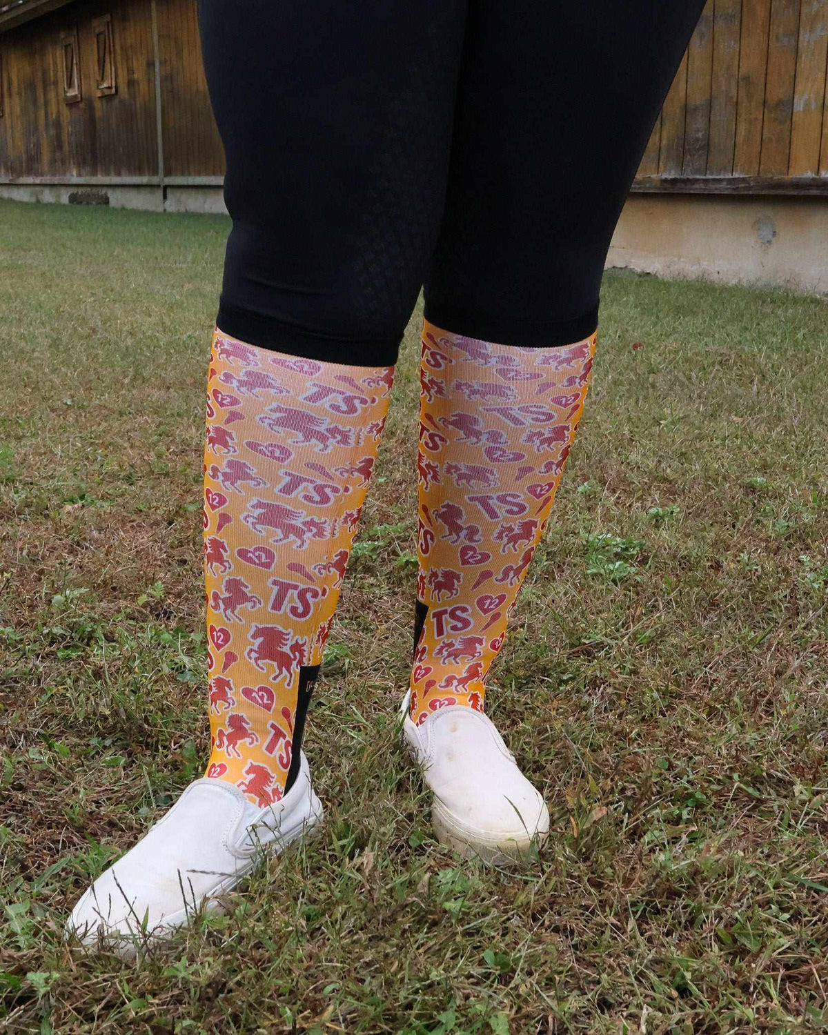 Limited edition Life of a Horse ShowGirl boot socks with colorful horse patterns, worn with black leggings and white shoes outdoors