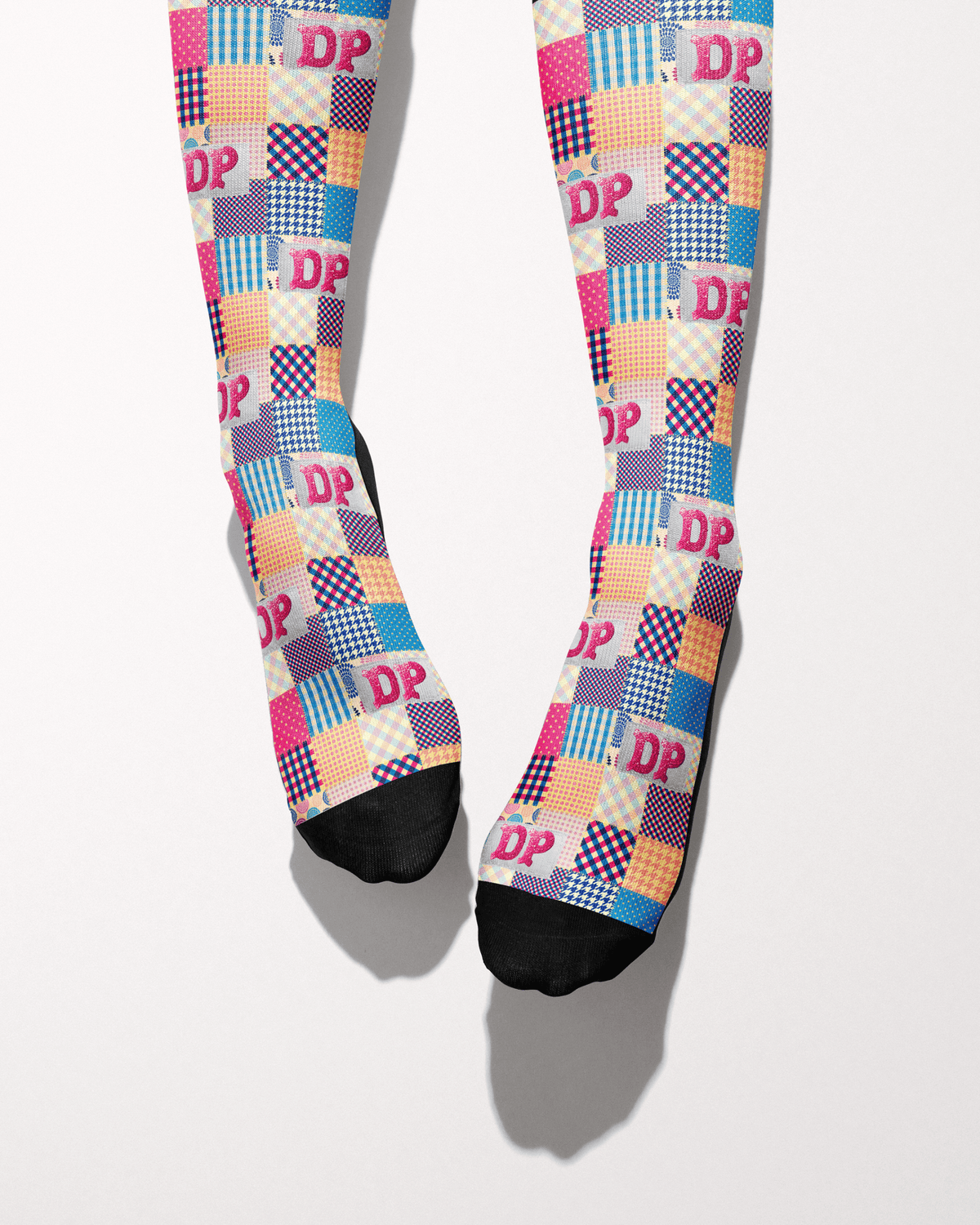 Socks of Many Colors socks shown on bare feet, black toes and heels against the patchwork print