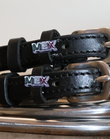 Close-up of MEX lettering charms on black leather spur straps over a silver spur