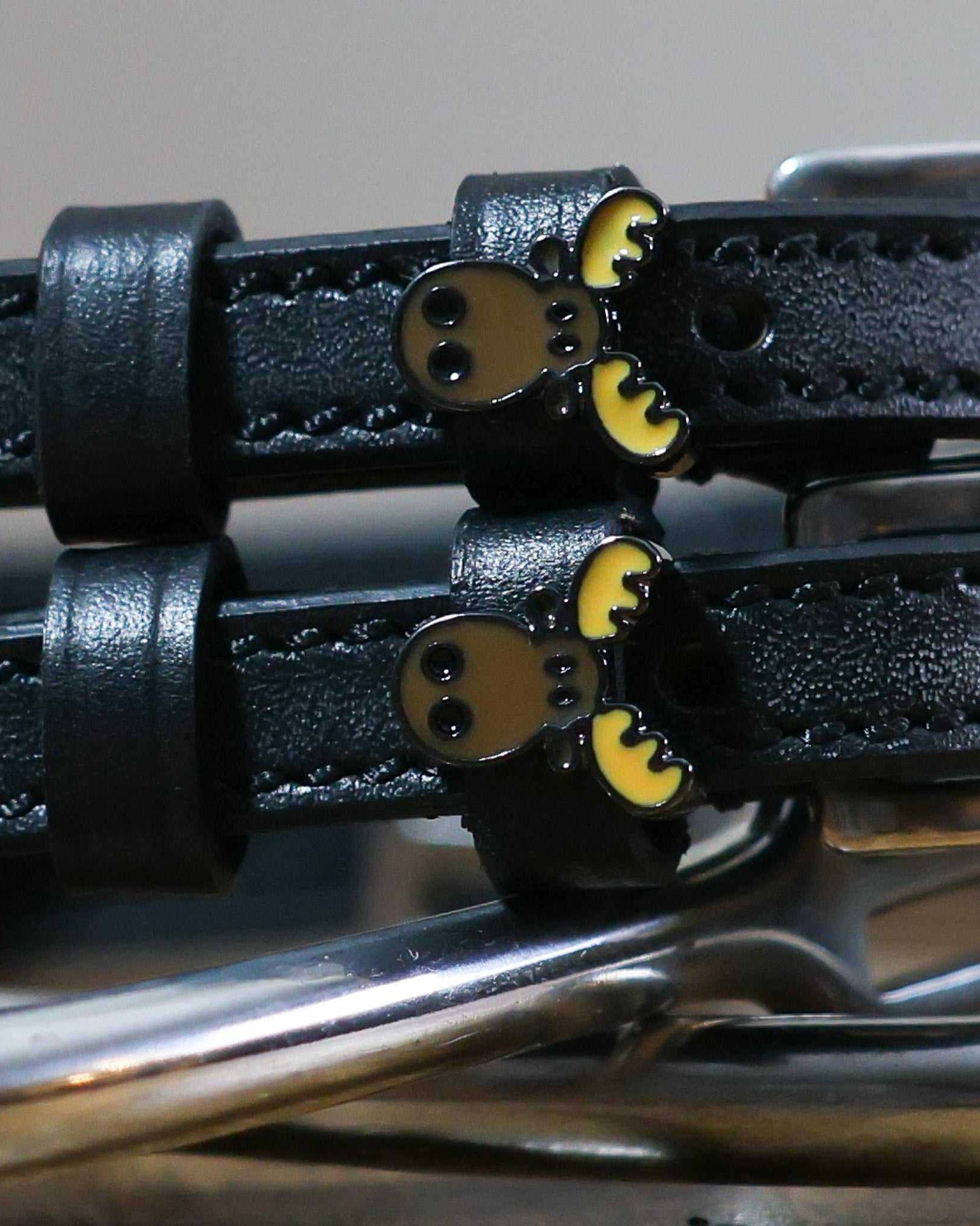 Close-up of brown moose head charms on black leather spur strap keepers