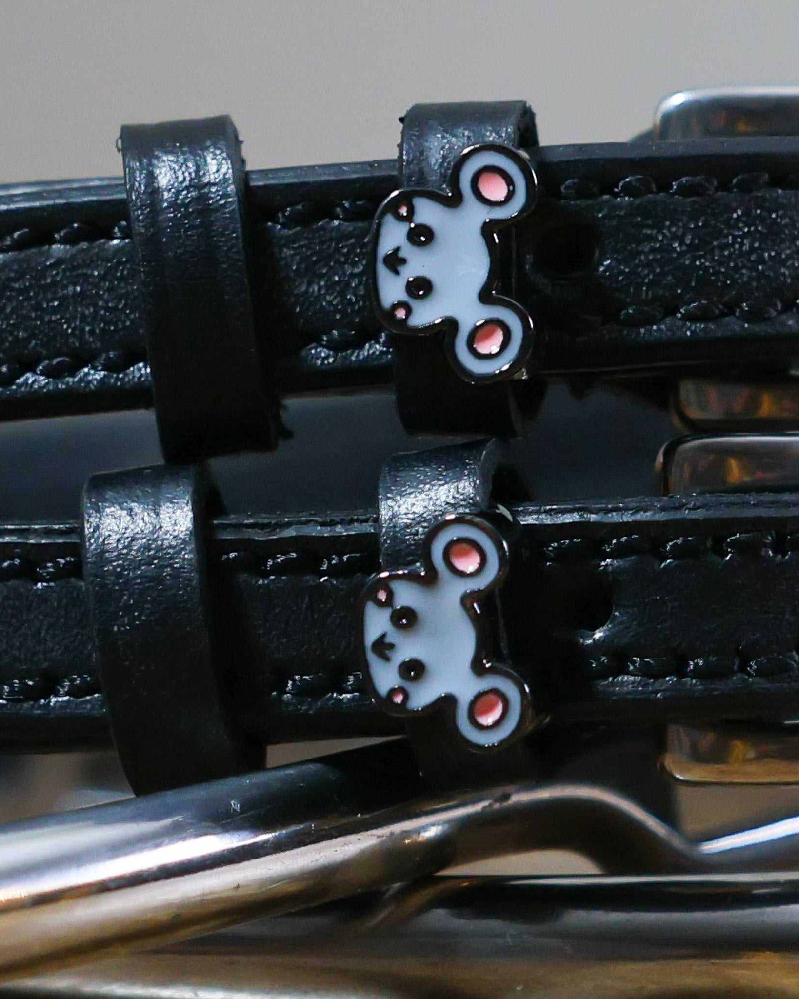 Close-up of grey mouse face charms on black leather spur straps over spur hardware