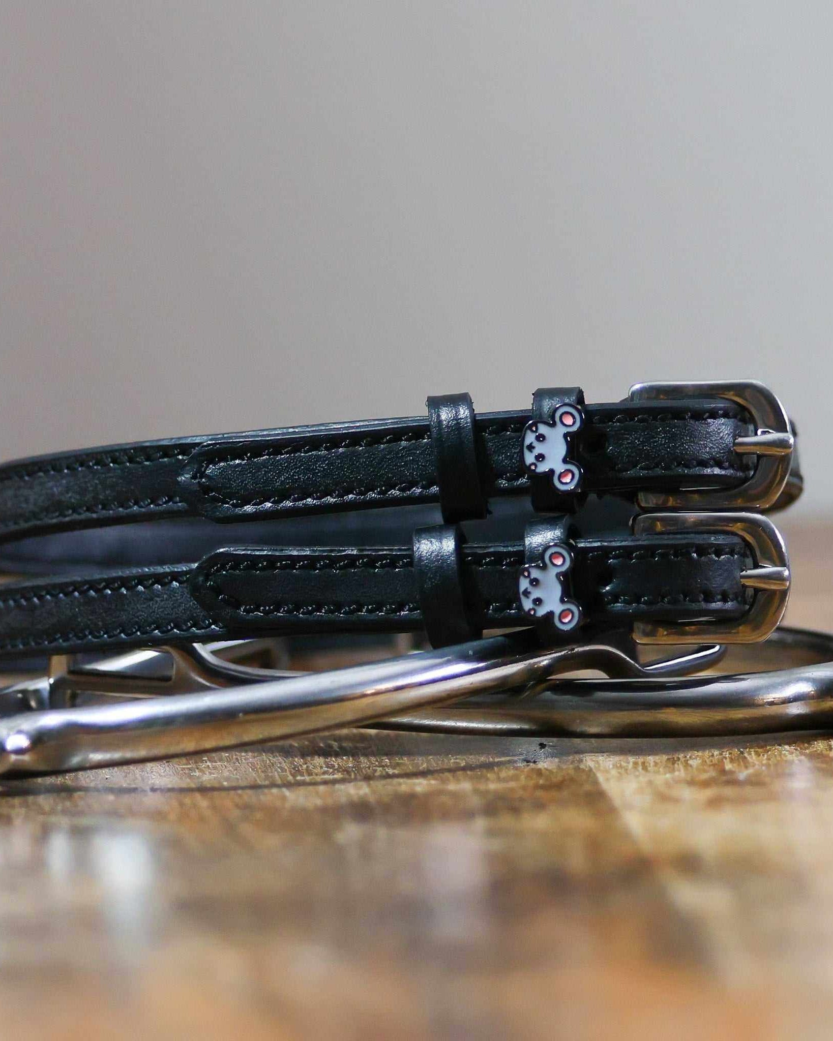 ManeJane Mouse spur straps coiled beside silver spurs on a wooden table