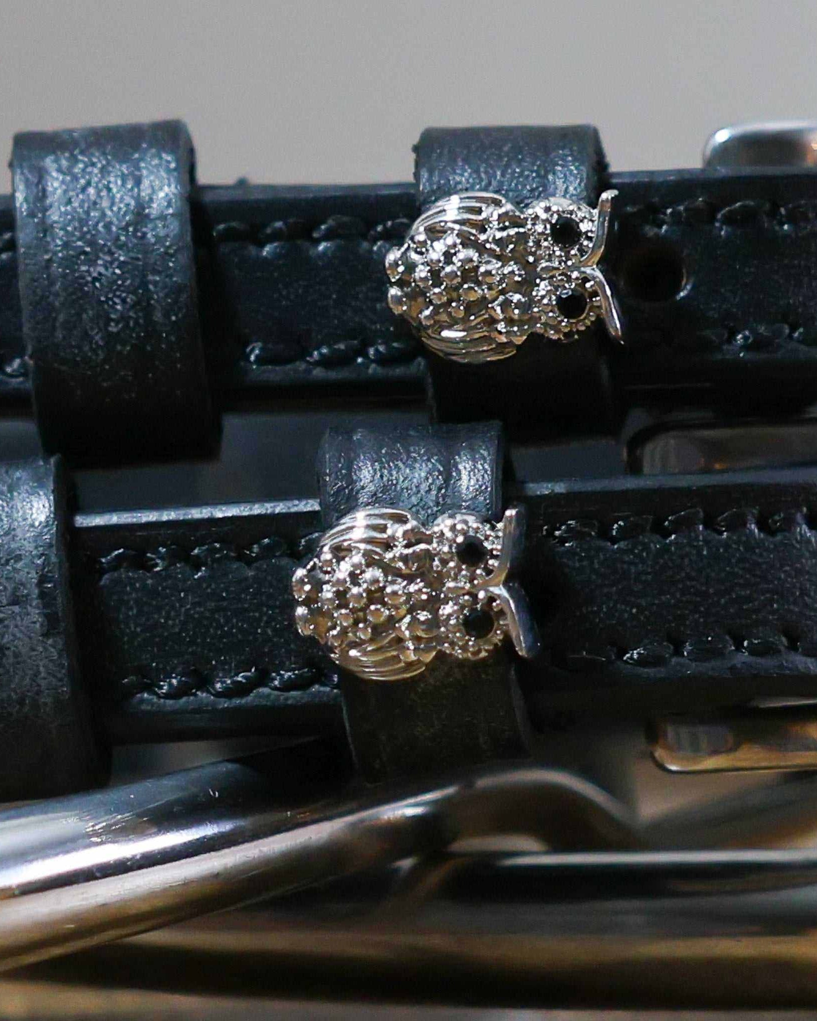 Close-up of sparkling crystal owl charms on black leather ManeJane spur strap keepers