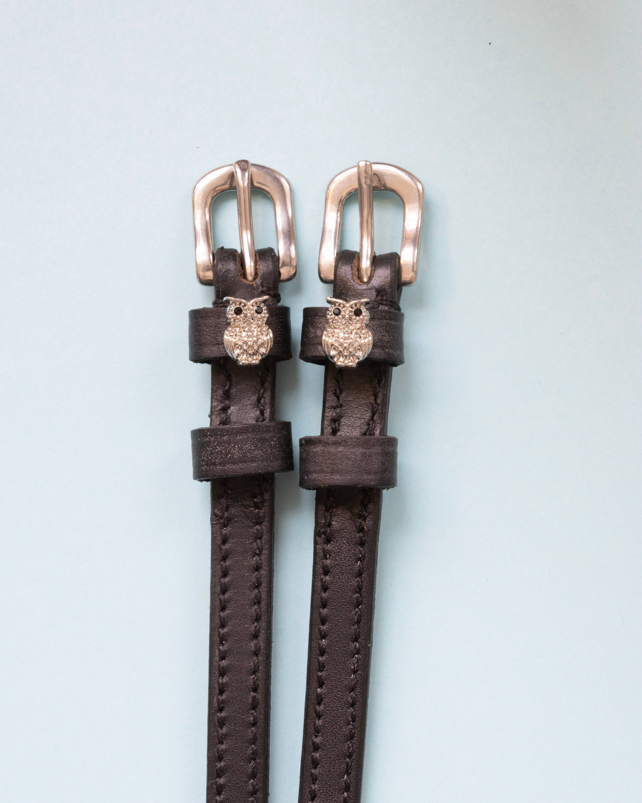 Dark brown leather ManeJane owl charm spur straps with silver buckles on pale mint