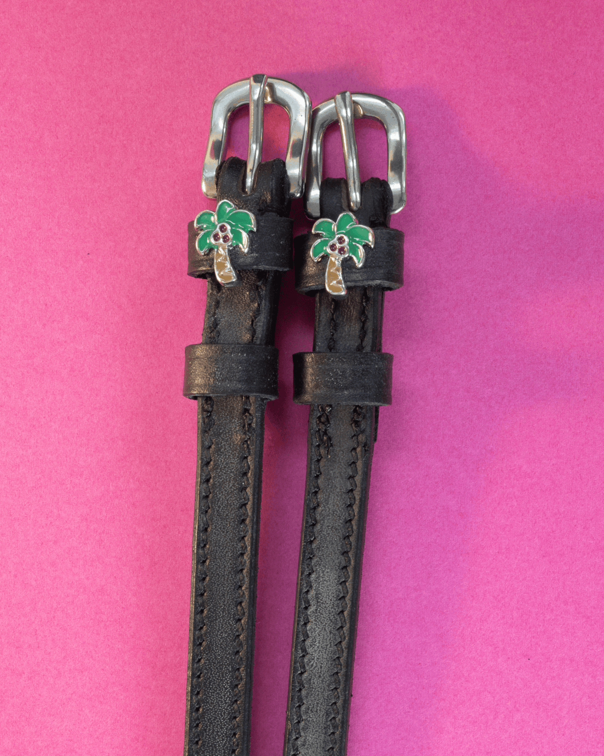 Black leather ManeJane spur straps with green palm tree charms on hot pink