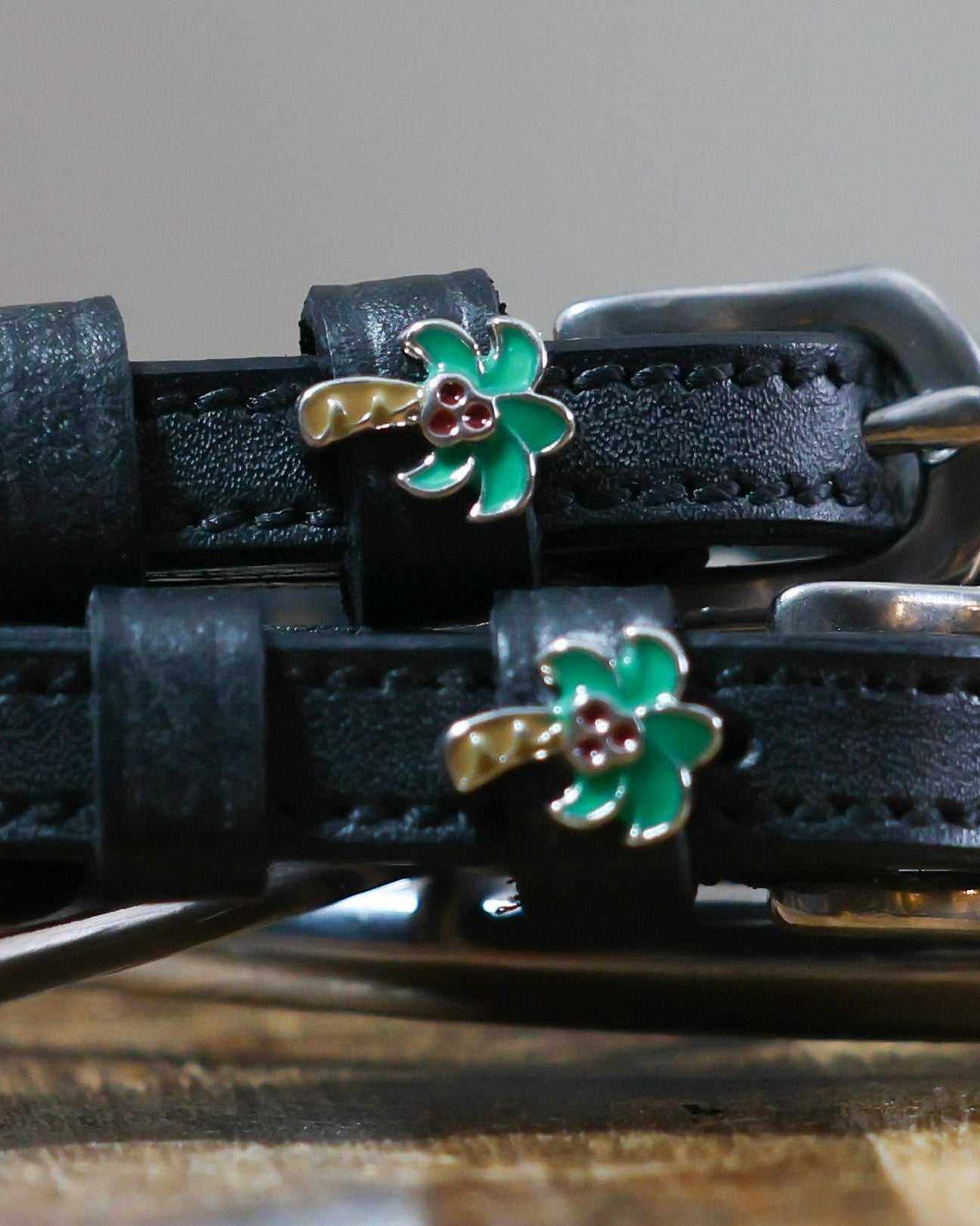 Close-up of enamel palm tree charms on black leather spur strap keepers