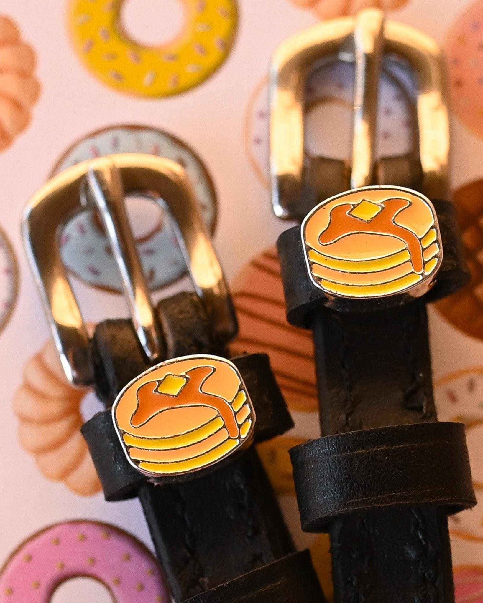 Detail of gold buckles and pancake charms on ManeJane spur straps over a donut print