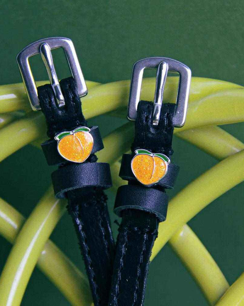 Black leather peach spur straps draped over a yellow coil on green