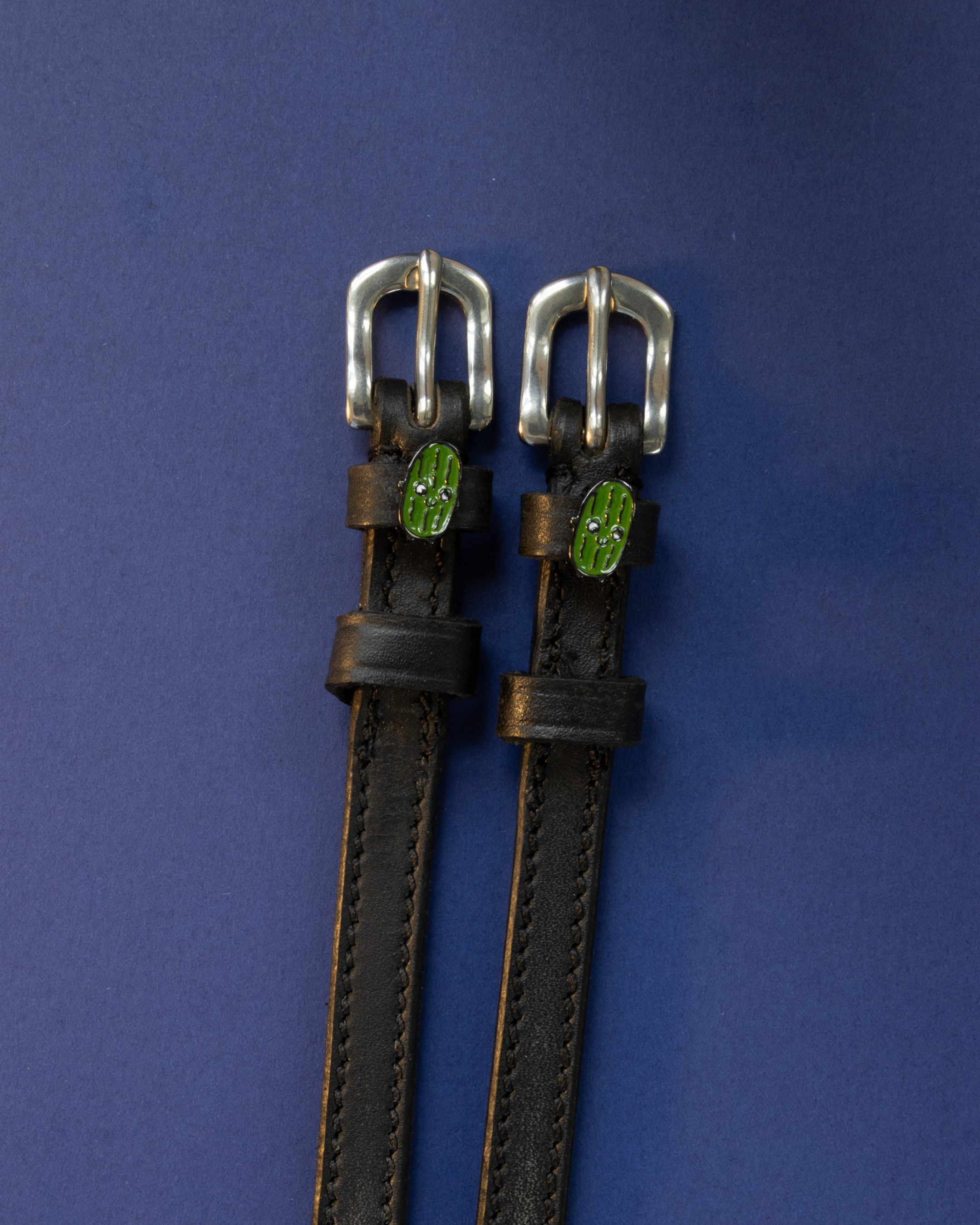 Black leather ManeJane pickle spur straps with silver buckles on navy blue