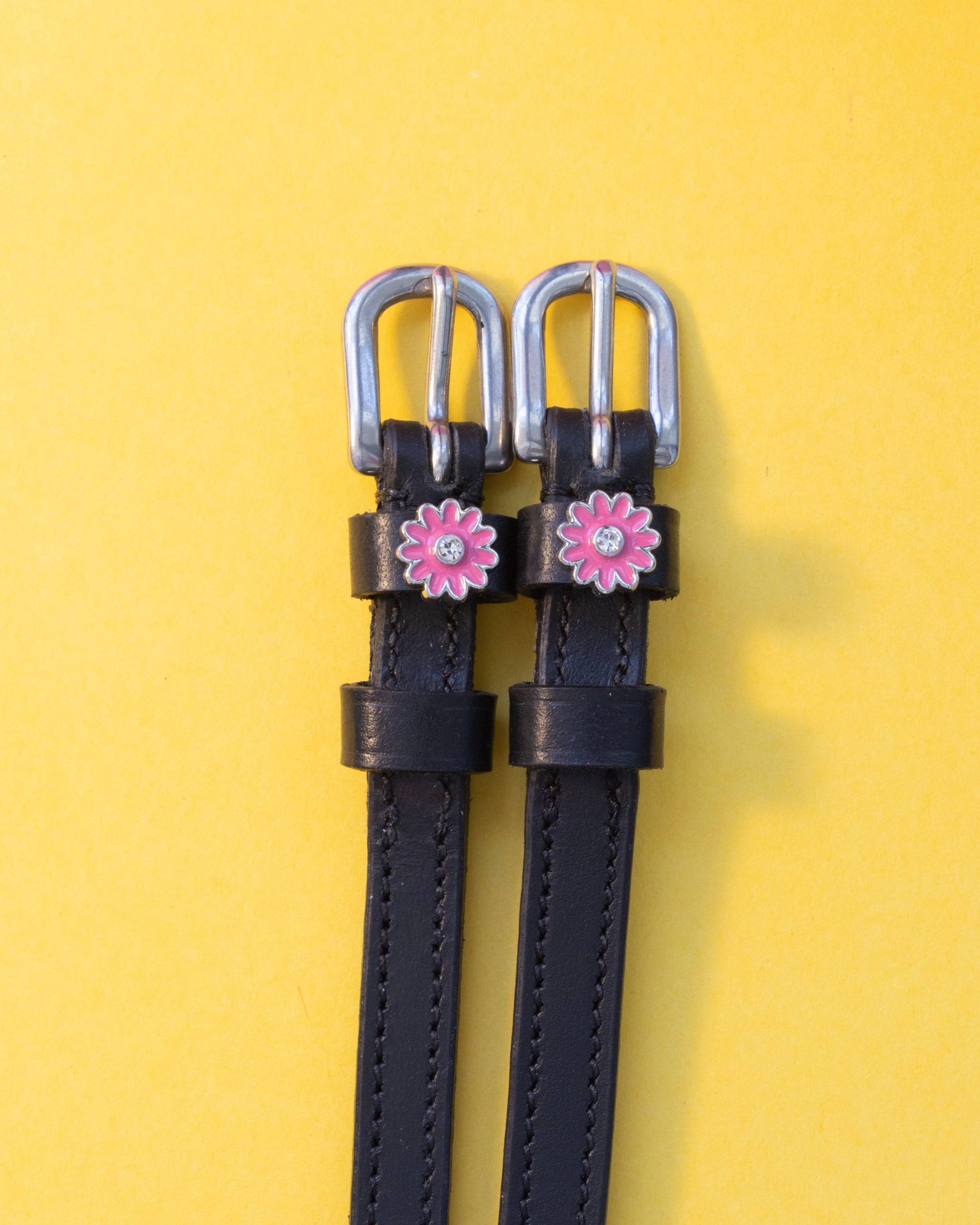 ManeJane pink flower spur straps with silver buckles on a yellow background