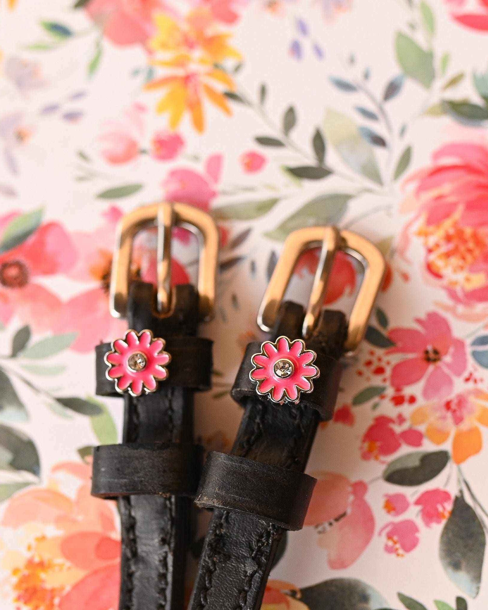 Pink flower spur strap gold buckle ends against a watercolor floral background