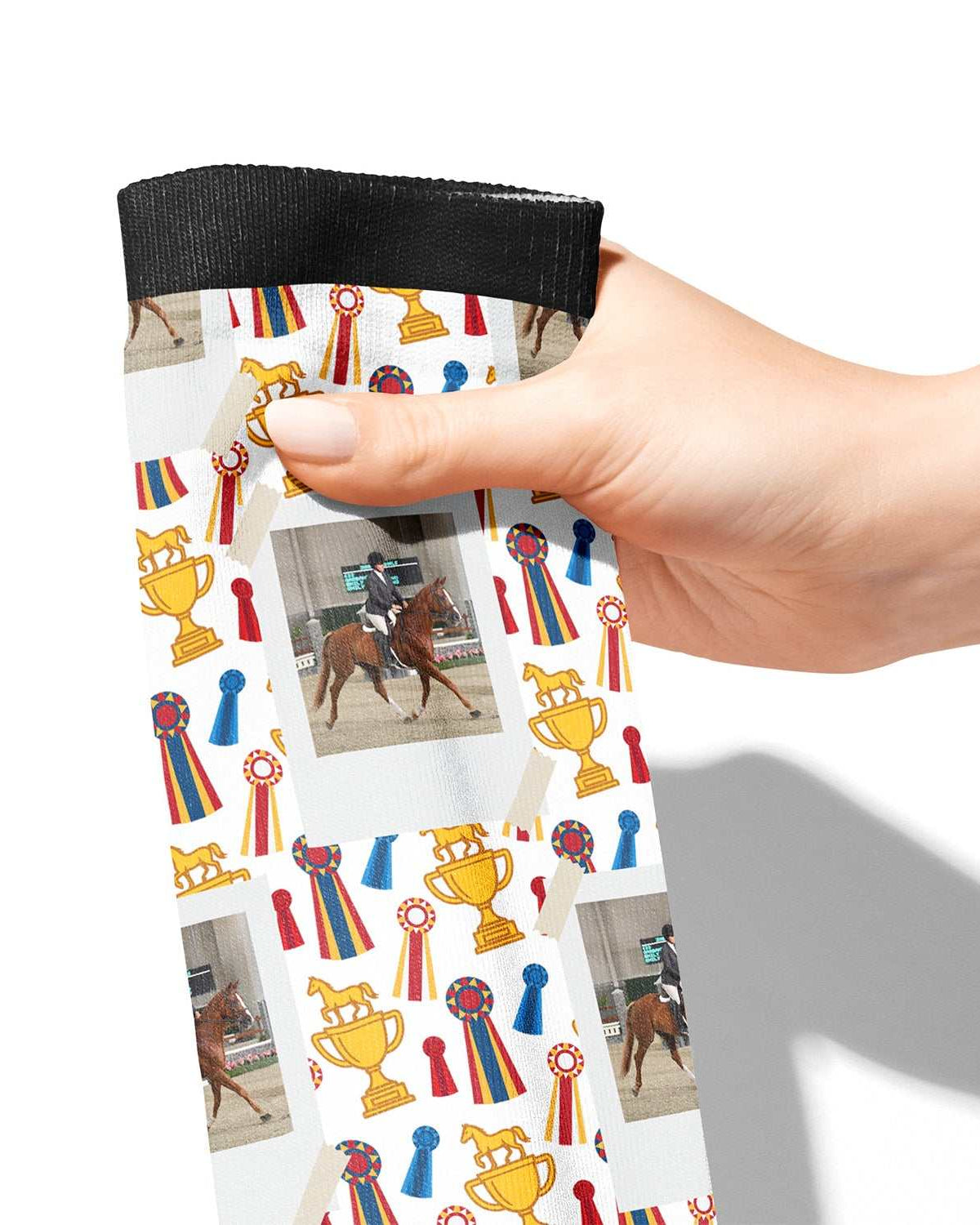 Hand holding custom boot socks with horse, trophy, and ribbon design pattern