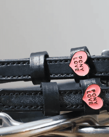 Detail of pink Pony Love heart charms on black leather ManeJane spur straps