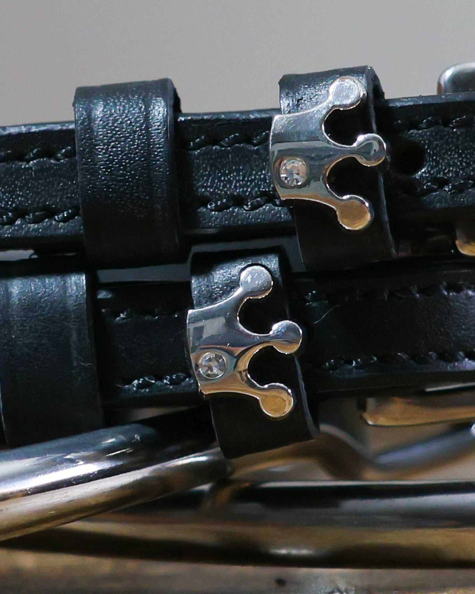 Close-up of silver crown charms with rhinestones on black leather spur strap keepers
