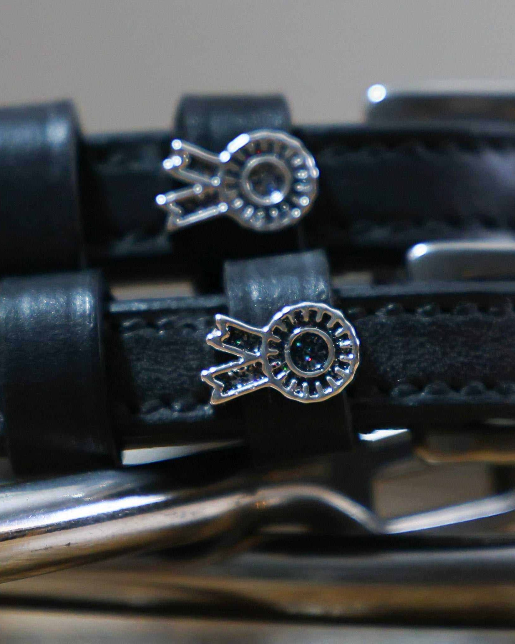 Close-up of silver prize-rosette charms with crystal centers on black spur straps