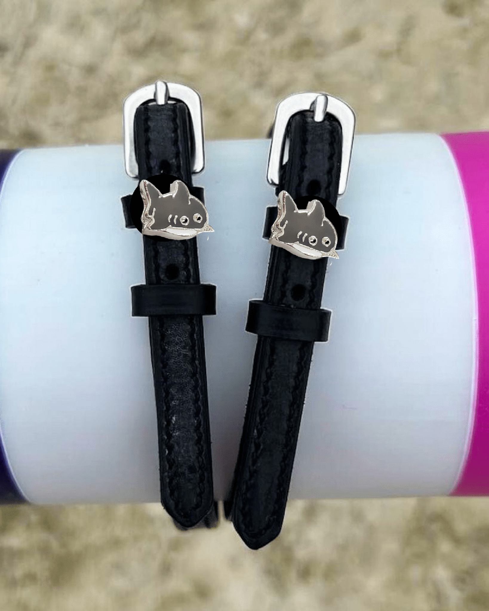 Black shark spur straps wrapped around a colorful tumbler outdoors, lifestyle shot
