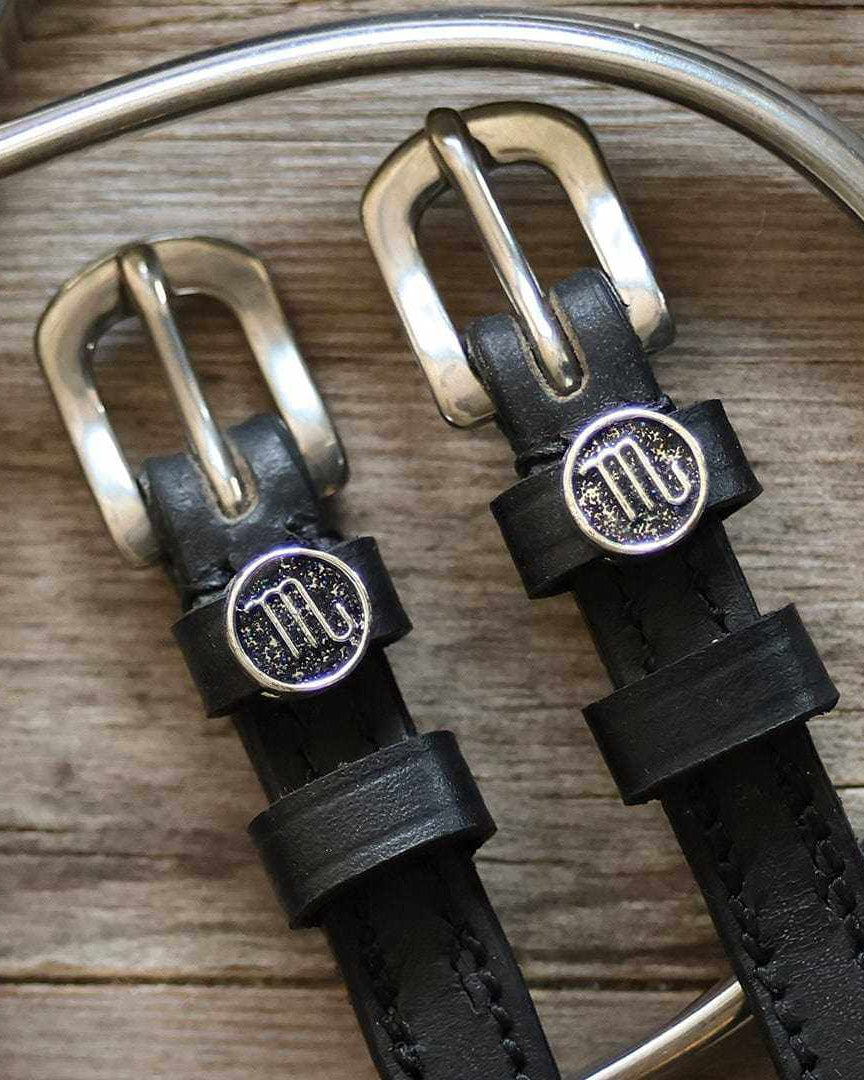 Silver Scorpio medallion spur straps buckled, close-up on a weathered wooden surface