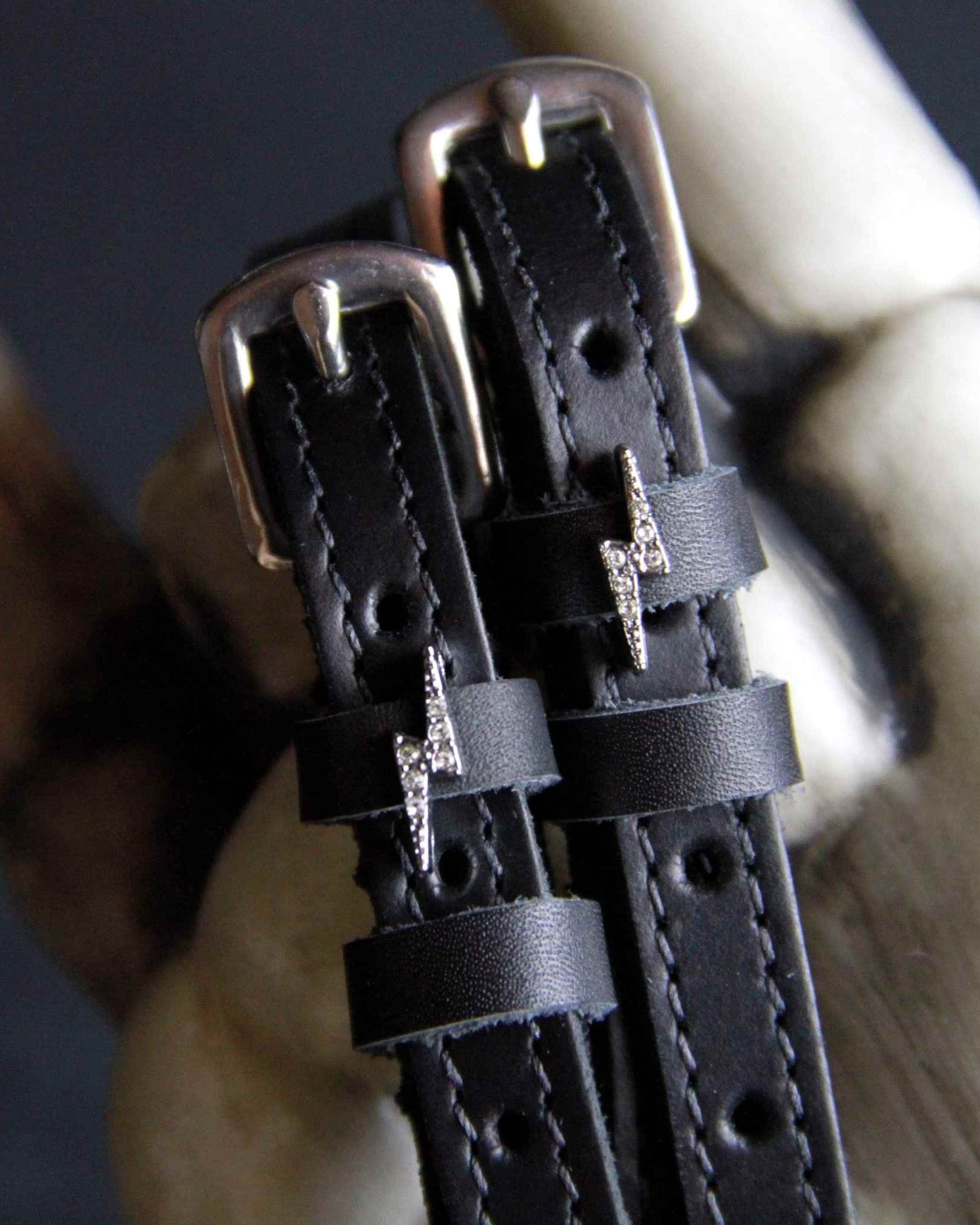 Close-up of rhinestone bolt charm spur straps resting against a pale bone prop