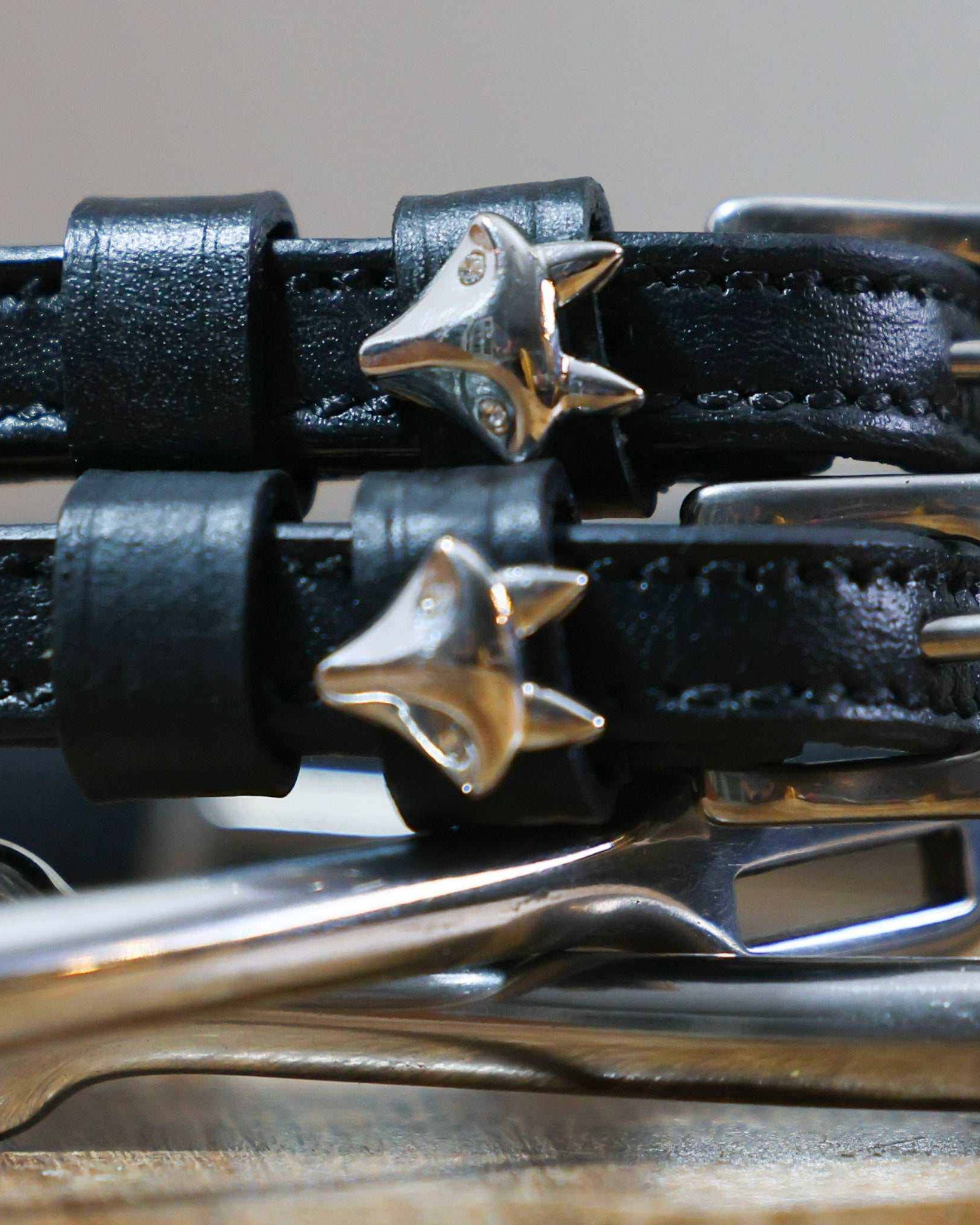 Close-up of silver fox head charms on the keepers of black leather spur straps