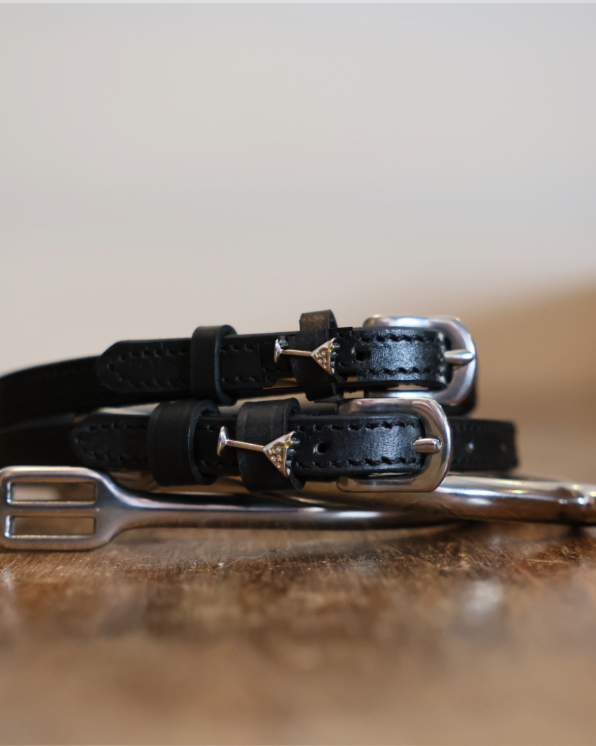 ManeJane martini glass spur straps stacked on a silver spur on a wooden table