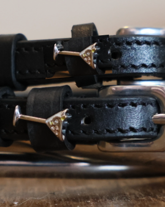 Close-up of silver martini glass charms on black leather ManeJane spur strap keepers