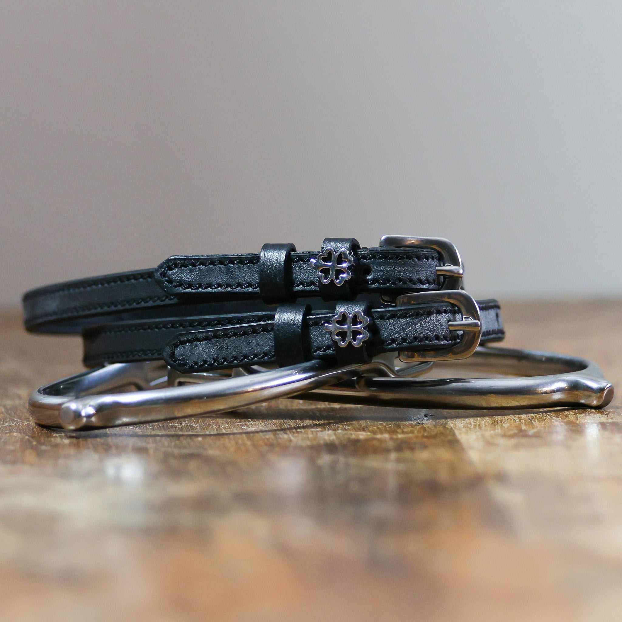 Coiled black leather clover spur straps on a silver spur, openwork silver clover charms