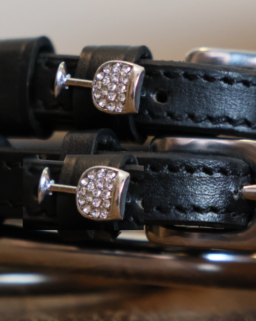 Close-up of rhinestone wine glass charms on black leather spur strap keepers