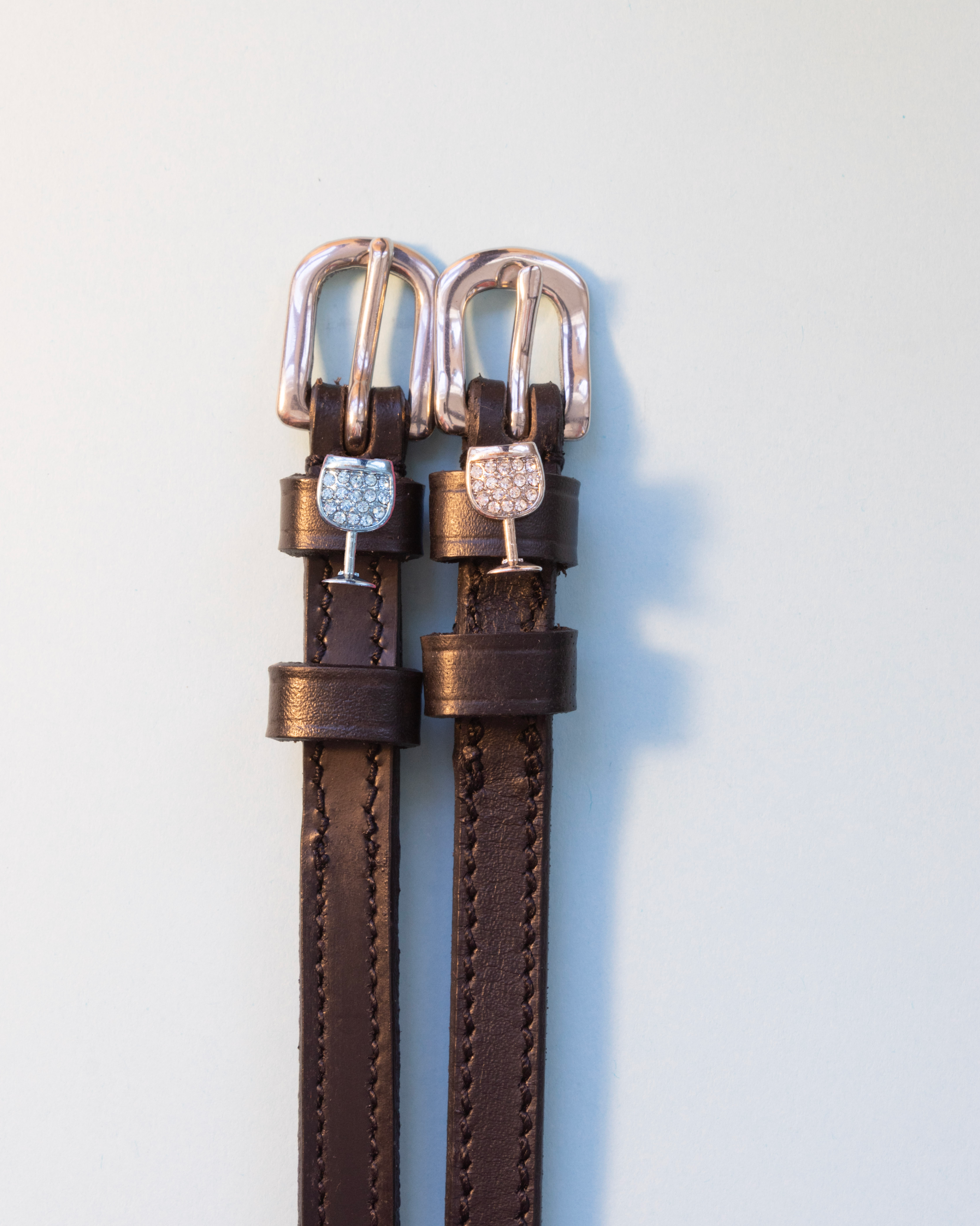 Brown leather crystal wine glass spur straps with rose gold buckles on pale grey